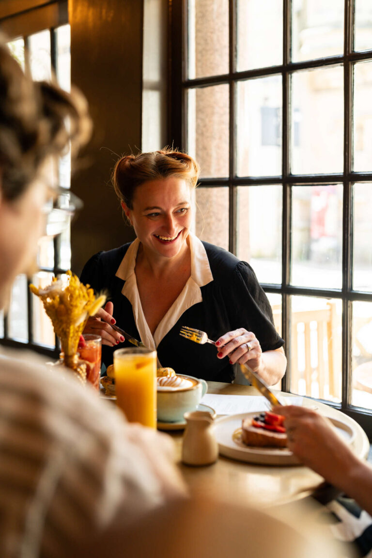 lady laughing and eating with friends in the Pub