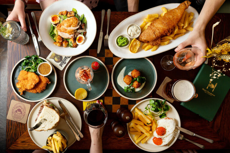 Food - Breakfast - Lunch - Dinner - Bristol - Horts Townhouse - Overhead view of a table of food - fiah & chips, caeser salad, staek sandwich, prawns, croquettes & fish & chips